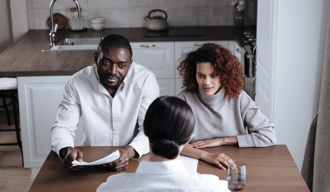 Man en vrouw bespreken samen de afspraken voor hun online echtscheiding met een adviseur aan tafel