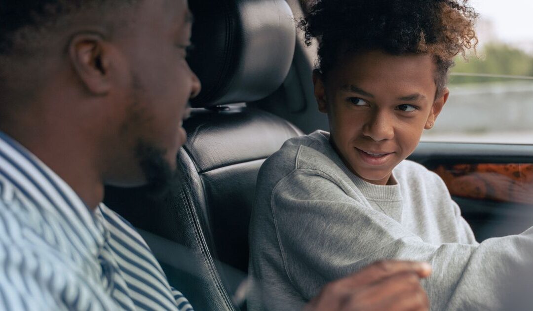 Vader en zoon tijdens een rijles in de auto, een mijlpaal voor kinderen na de scheiding